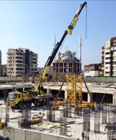 Yüksek bir bina inşaatının yanında malzeme kaldıran kamyon üstü vinç